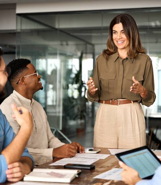 Happy middle aged business woman leader working with diverse team at meeting.